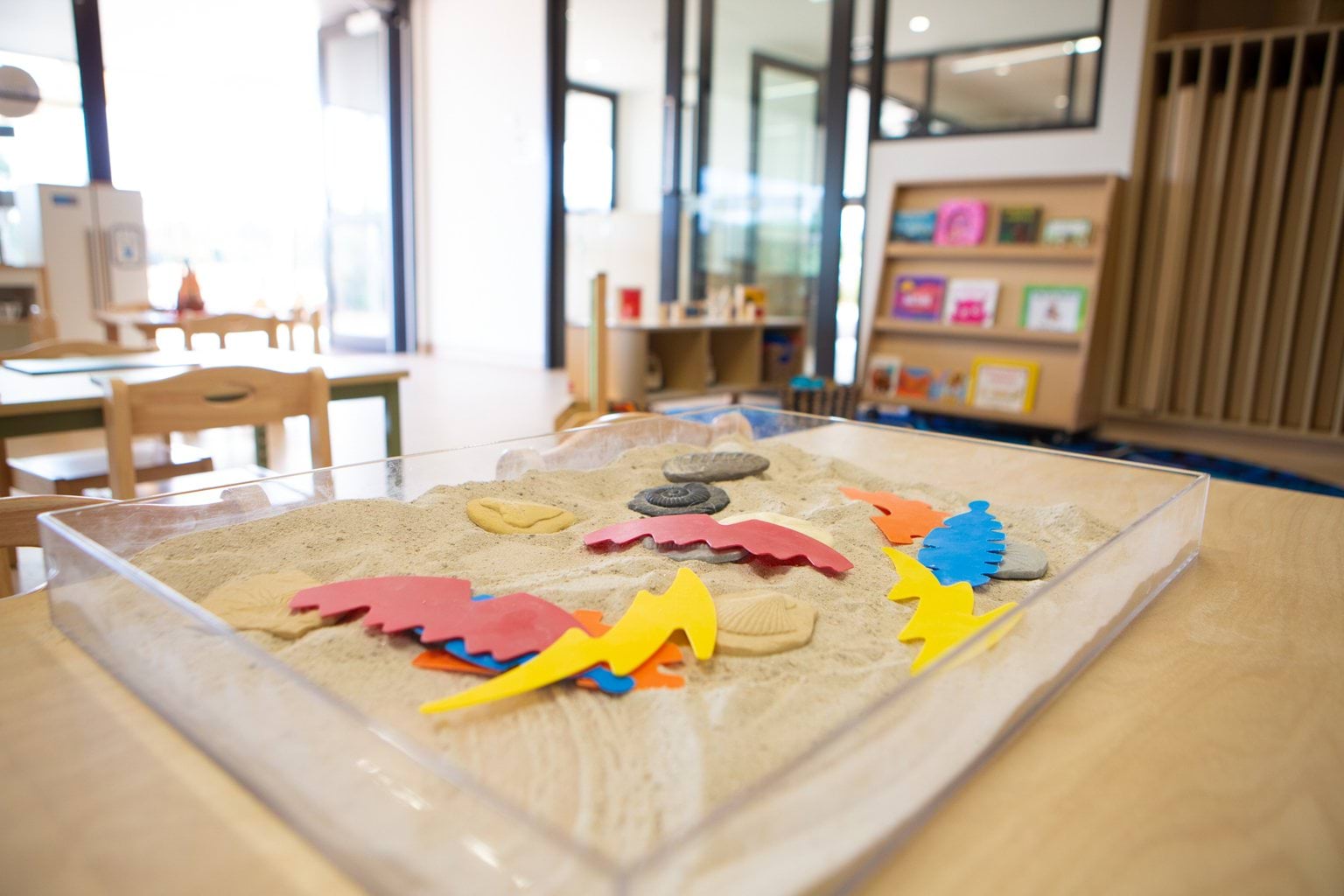 Sensory sandbox toy on table with picture books and doorway to outside at Early Learning Victoria Wimbi (Fawkner).