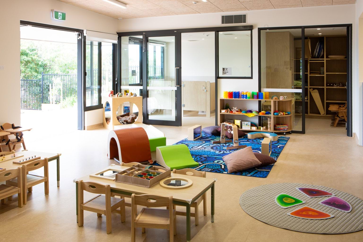 Wide view of Ngarrert room with rug, reading nook, highchairs and toys at Early Learning Victoria Wimbi (Fawkner).