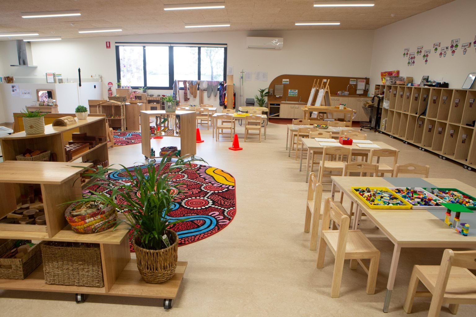 Alternate view showing storage shelves and lockers in Murtoa early learning centre with wooden furniture, pot plant, and dot art rug.