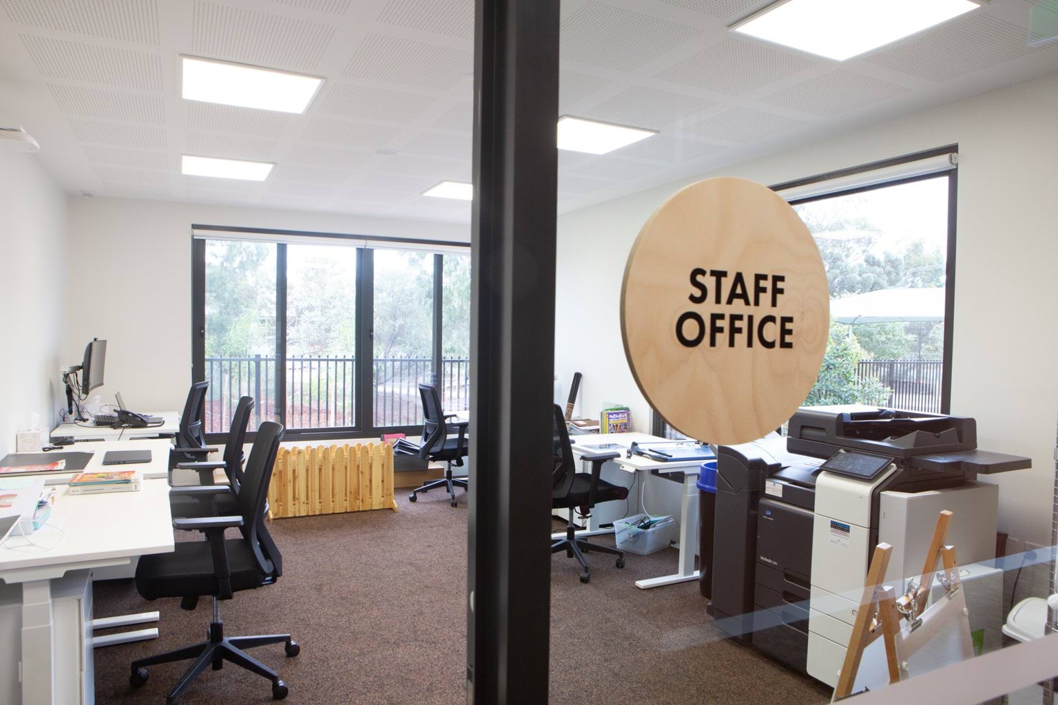 View into staff office at Early Learning Victoria Bani Walup (Murtoa) with wooden sign on glass, desks and printer inside.